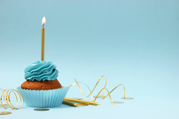 Delicioso cupcake con una vela en un fondo de color con espacio para insertar texto. Historia fecunda, cumpleaños. - Foto, imagen