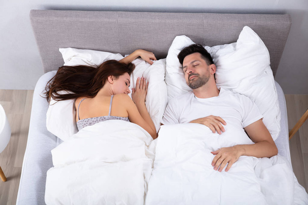 Вид спящей на кровати молодой пары
 - Фото, изображение