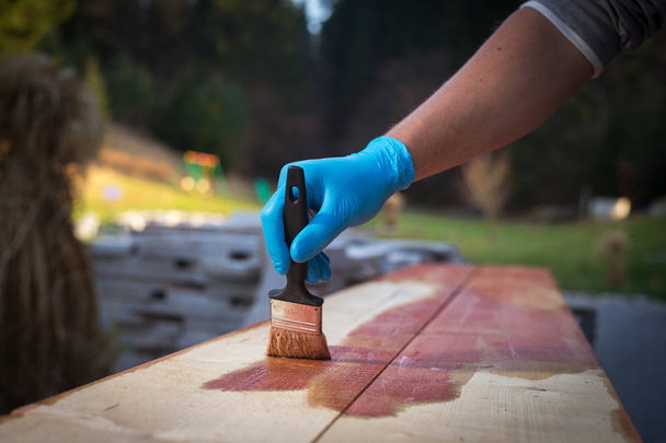 Hand applying copper based preservative on wood to prevent insect attack and fungal decay: Wood preservation from weathering, wood staining, carpentry. - Photo, image