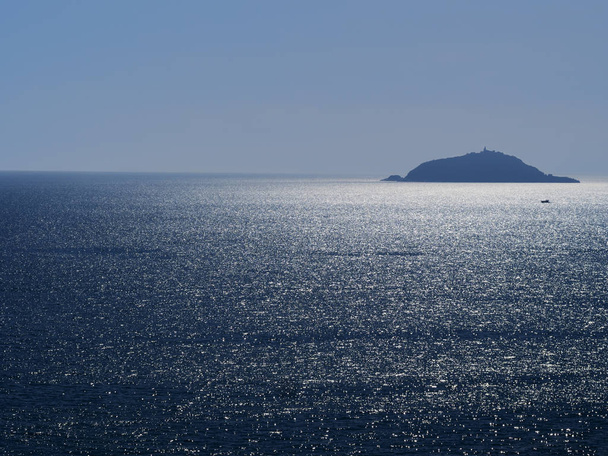 Isla Tino cerca de Portovenere, Liguria. La luz del sol brilla en el mar plateado. Idílico, con bote pequeño
. - Foto, imagen