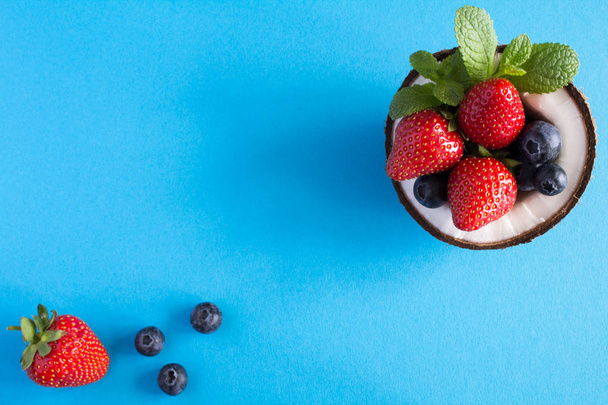 Coconut,strawberry and blueberries  on the blue background.Top view. - Photo, image