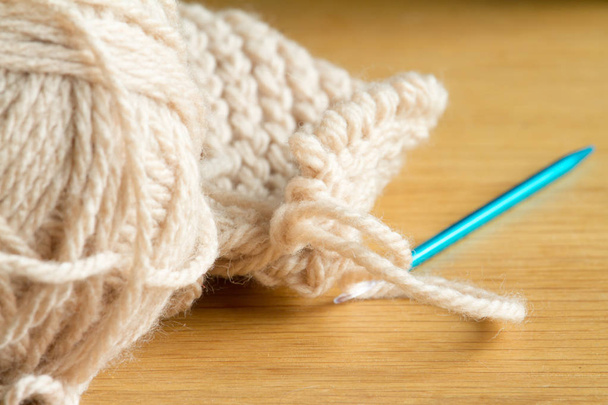 Extremely close-up knitting from beige yarn, needle, crochet hooks. Work on a new product. Selective soft focus. - Photo, Image