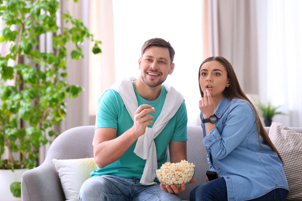 Couple watching movie with popcorn in living room - Fotoğraf, Görsel