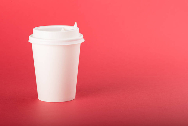 White disposable paper cup with white cap on a red background - Valokuva, kuva