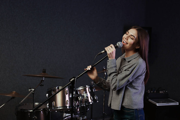 Young singer with microphone recording song in studio. Space for text - Foto, Imagen