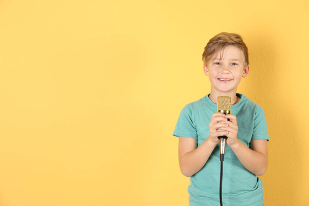 Cute boy with microphone on color background. Space for text - Foto, afbeelding
