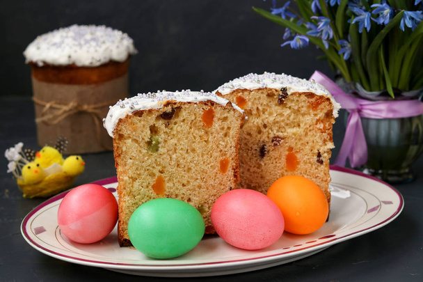 Easter cakes and colorful eggs are located on a plate on a dark background - 写真・画像