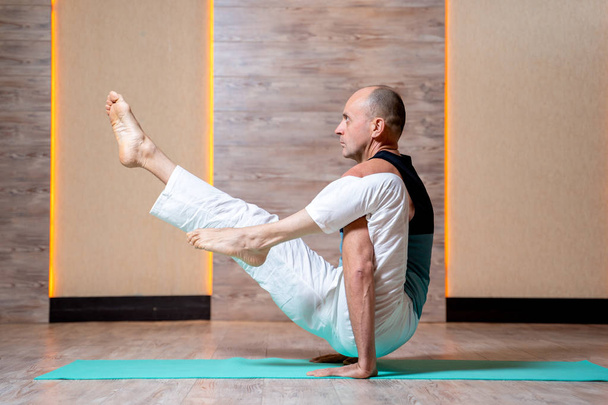 Man practices yoga while standing on hands on blue mat . - Foto, Imagem
