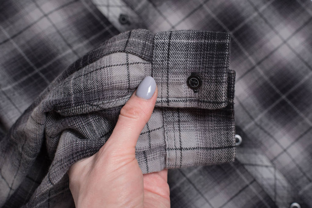 Sleeve of gray checkered shirt in female hand. Close-up - Photo, Image
