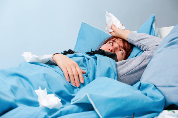 Photo of sick woman with paper handkerchiefs lying on bed - Φωτογραφία, εικόνα