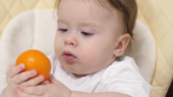 Dítě s mandarinka sedí u stolu. - Záběry, video