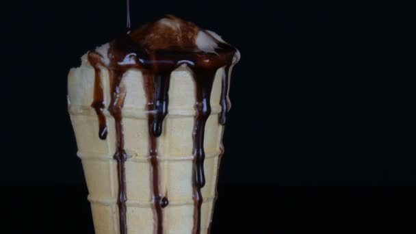 Olvadó fagylaltot, amely önti csokoládé szirup mártással, fekete háttér - Felvétel, videó
