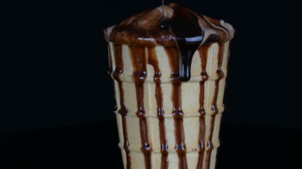 Melting ice cream on which pours chocolate syrup sauce on black background - Footage, Video
