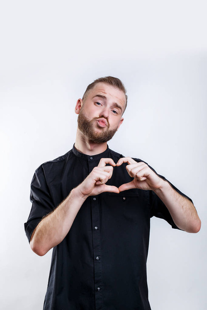 Friendly attractive bearded male makes heart gesture,, wears spectacles and black shirt - Foto, immagini