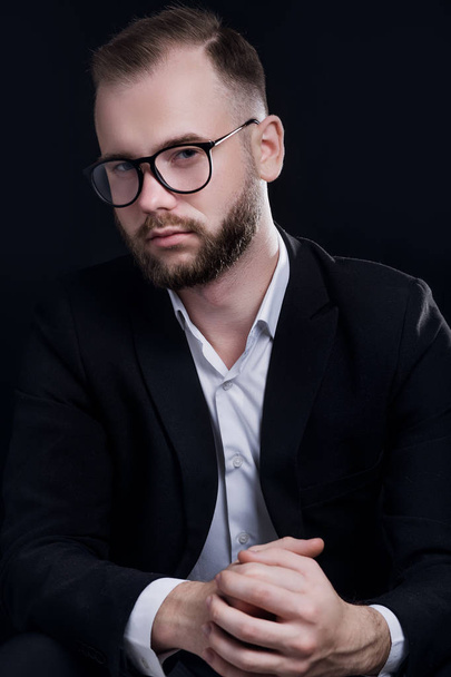 Handsome young man in black suit and glasses on black background - Foto, Imagem