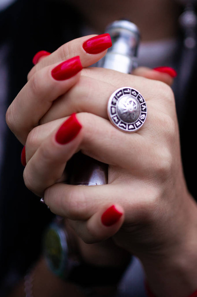 Biała kobieta z czerwonymi paznokciami manicure i zabytkowy pierścień na palcu trzyma małe vape. Palenie alternatywne vay. Życie bez papierosów. Kobieta-vaper. Mały e-papieros. - Zdjęcie, obraz
