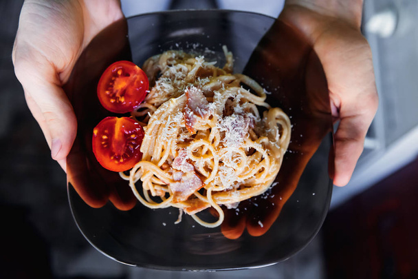 a man holds a plate with an appetizing dish. pasta with cheese a - Photo, Image
