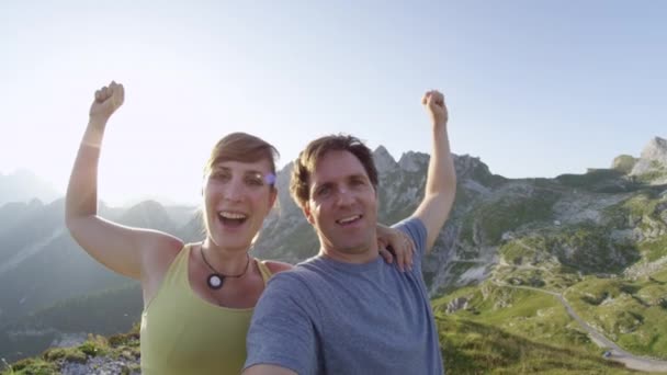Selfie portré: Elated fiatal pár vesz selfie a hegytetőn nyáron. Vidám túrázók fújja le a gőzt egy hosszú kirándulás után. Győzedelmes Trekkers outstretching fegyverek után elérte hegycsúcs. - Felvétel, videó