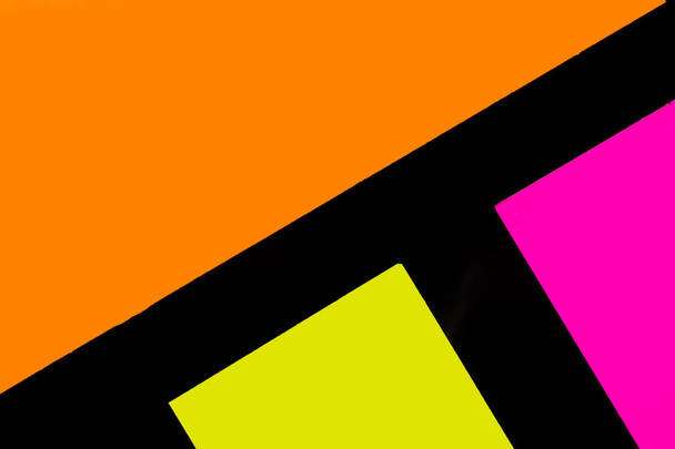 Gele, oranje en paarse kleurrijke kantoorstickers op zwart papier. Kantoor noteparer als herinnering. geïsoleerd op zwart papier. - Foto, afbeelding
