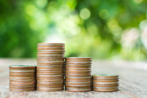 Montón de monedas en mesa de madera con fondo hoja verde borrosa, Ahorre dinero y concepto de inversión
 - Foto, imagen