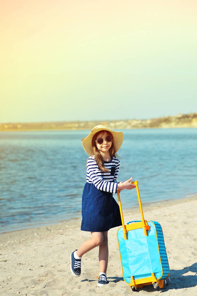 Cute little girl in hat with suitcase on the beach. Summertime concept. - Foto, Imagem