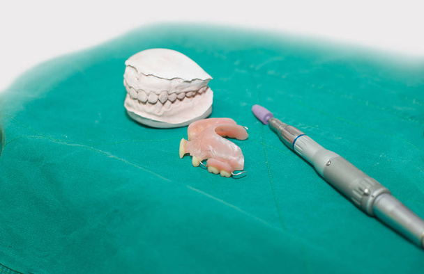Prothesen und Zahnarztwerkzeuge in grünem Stoff Hintergrund. - Foto, Bild