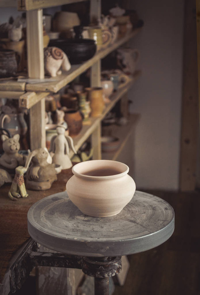 Tontopf im Vordergrund und Regale mit Keramik - auf der zweiten - Foto, Bild