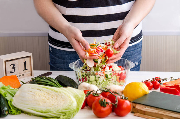 Mains de femme ajoutant des légumes aux plats
 - Photo, image