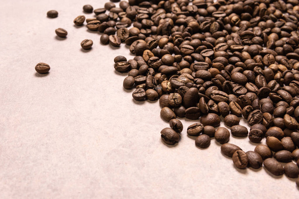 geröstete Kaffeebohnen in großen Mengen auf hellrosa Hintergrund. dunkles co - Foto, Bild