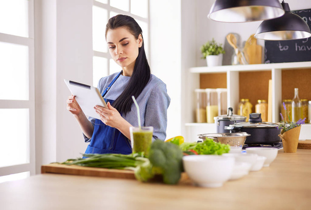 Young woman using a tablet computer to cook in her kitchen - Fotoğraf, Görsel
