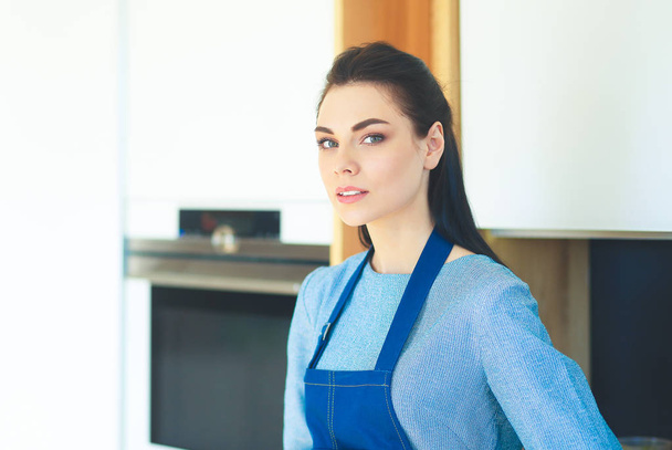 Portrait of young woman standing with arms crossed against kitchen background - Fotografie, Obrázek