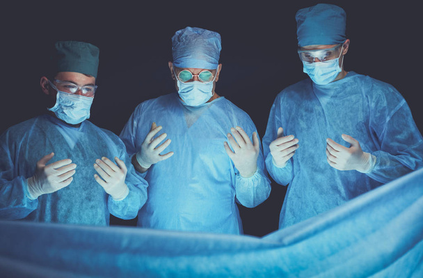 Μια ομάδα χειρούργων στο χειρουργείο με μπλε χρώμα. Ιατρική ομάδα που εκτελεί λειτουργία - Φωτογραφία, εικόνα
