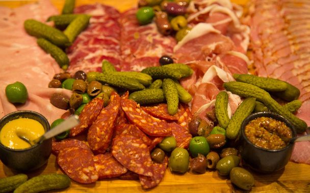 Sliced ham meat olives pickles dips appetizer assorted  tray top view  - Photo, Image