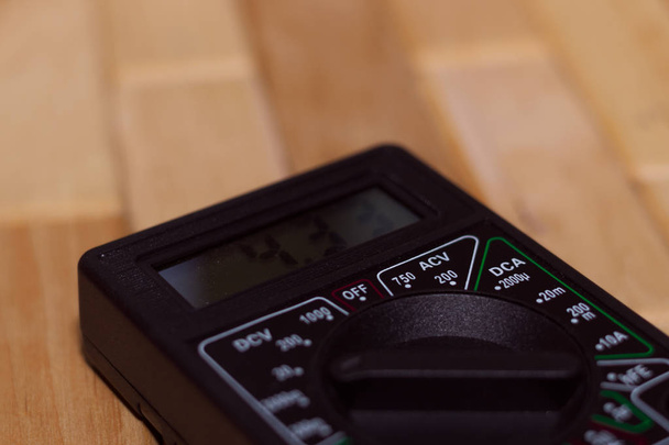 Digital measuring multimeter on wooden floor. It shows 4.33V or fully charged battery. Includes voltmeter, ampermeter, ohmmeter. - Photo, Image