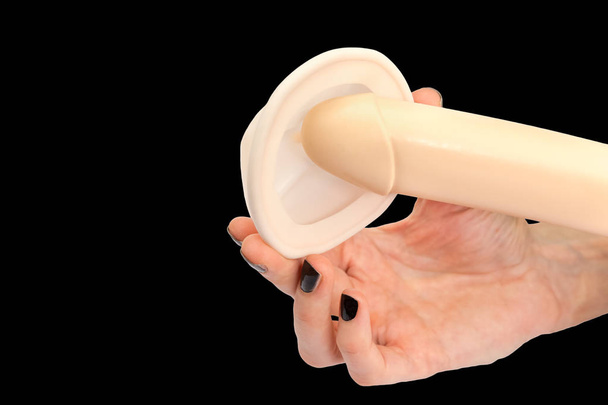 La mano femenina sostiene el modelo de pene humano y pesario
 - Foto, Imagen