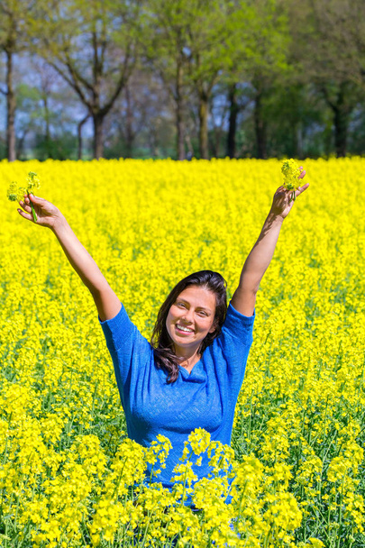 Onnellinen nuori nainen kädet ylös keltainen rypsi alalla
 - Valokuva, kuva