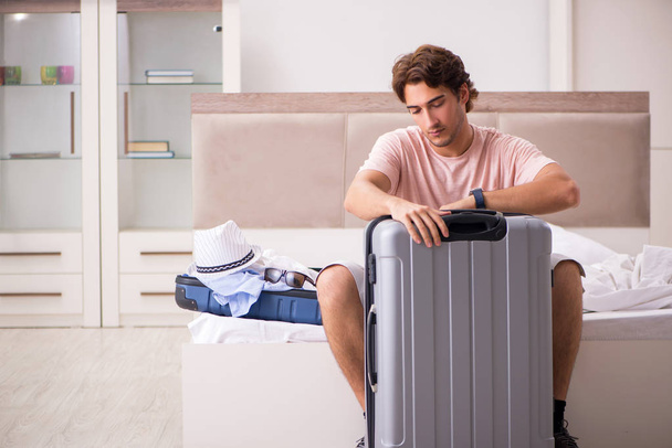 旅行を待っている寝室でスーツケースを持つ男  - 写真・画像
