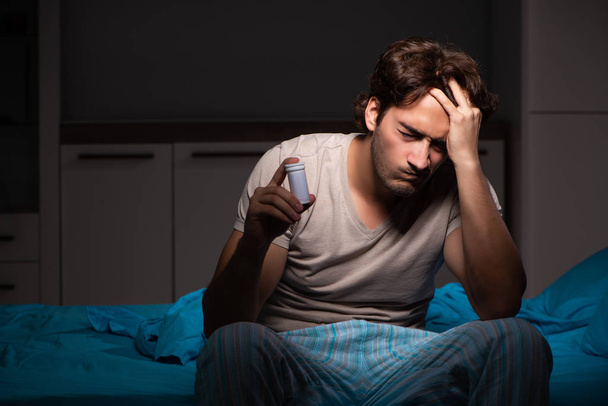 Zieke man in zijn bed met medicijnen - Foto, afbeelding