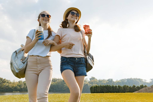 Girl friends are walking in the park in nature. Girls walk along the green lawn, talk, have fun - Photo, image