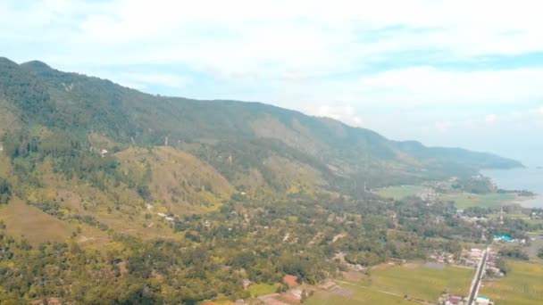 Aerial: Lake Toba en Samosir Island uitzicht vanaf boven Sumatra Indonesië. Enorme vulkanische caldera bedekt met water, traditionele Batak dorpen, groene rijstvelden, Equatoriaal bos. Groen blauw oranje sortering. - Video