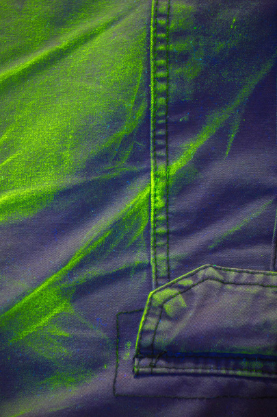 Promieniowanie ultrafioletowe pigmentu w świetle UV na szortach bawełnianych. Jaskrawość jest żółto-zielona i bardzo żywa. - Zdjęcie, obraz