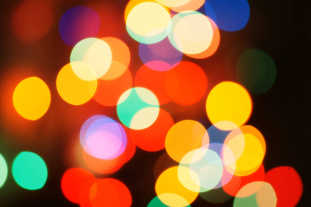 Multi-color holiday garland. Garland is blurred. Many colorful round lights. Fully defocused photo. Blurred background and foreground. Holiday mood. New Year and Christmas is coming. - Photo, Image