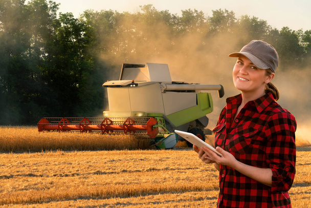Woman farmer uses a digital tablet control autonomous harvester. Smart farming concept - Foto, afbeelding