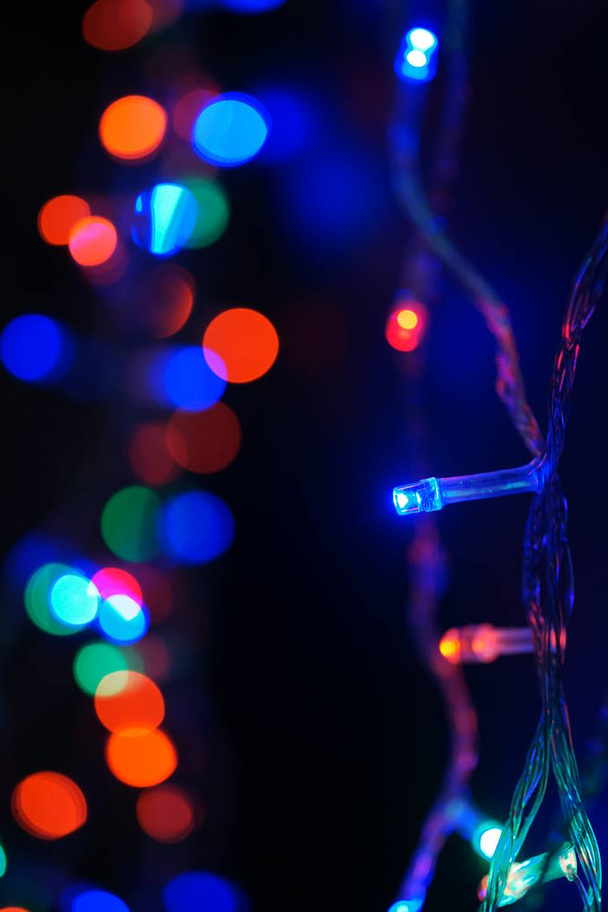 Többszínű kék ünnepi koszorú. A koszorú elmosódott. Sok nagy színes kerek fények. Teljesen hatástalanított fénykép. Homályos háttér és előtér. Üdülési hangulat. Újév és karácsony közeleg.. - Fotó, kép