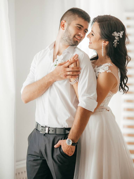 Beautiful and young bride and groom posing at room - Valokuva, kuva