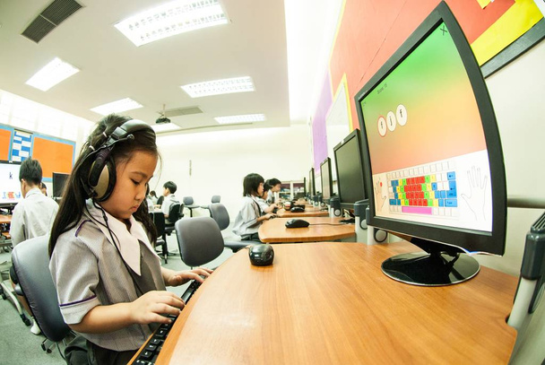 Asian child learning to use computer at elementary in classroom. - Photo, image