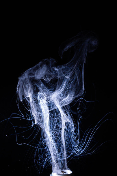 Vape smoke clouds isolated on black background. Hot vape liquid splash in vape coil. Nice aromatic cloud. Low light photo. Underexposed photo in a low key style.  - Fotó, kép