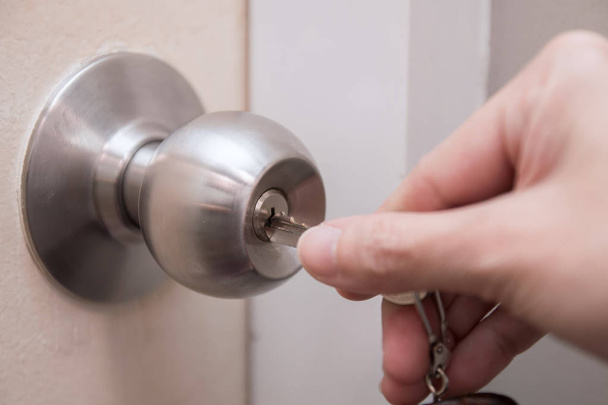 Beyaz kapı kilidini açmak veya kilitlemek için anahtarı kullanarak kadının elinin yakın - Fotoğraf, Görsel