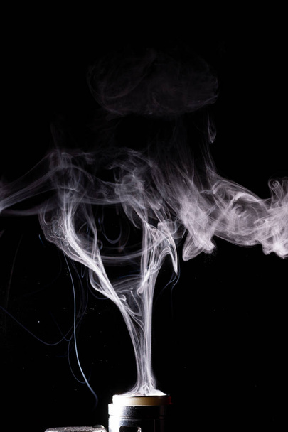 Вейп-хмари плескають на чорному тлі. Запас ізольований білий дим з розпилювачем киплячого гліцерину
. - Фото, зображення