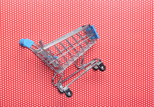 Mini carrito de compras para comprar en fondo rojo, concepto de consumidor, minimalismo, vista superior
 - Foto, Imagen